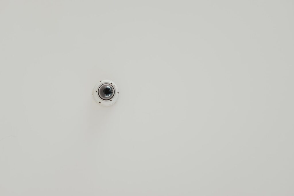 A surveillance camera mounted on a white wall.